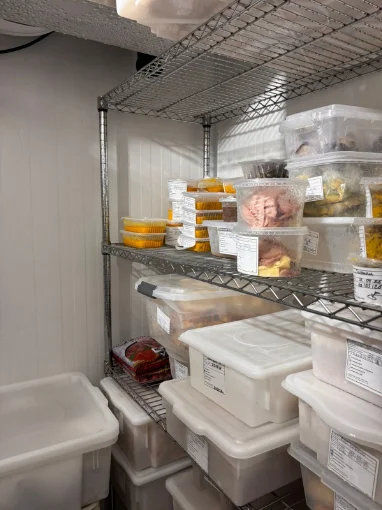 Câmara fria organizada com alimentos identificados e datados, seguindo boas práticas de armazenamento